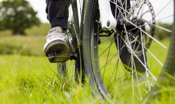 Zoom sur les pieds d'une personne en train de faire du vélo dans l'herbe