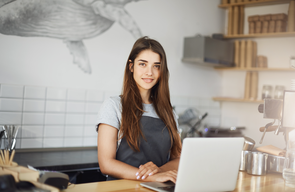Une femme au comptoir d'un café, il s'agit de la gérante elle est jeune et souriante