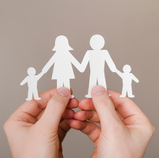 Photo avec deux mains qui tiennent un origami représentant les silhouettes d'une famille dite nucléraire (deux parents et deux enfants)