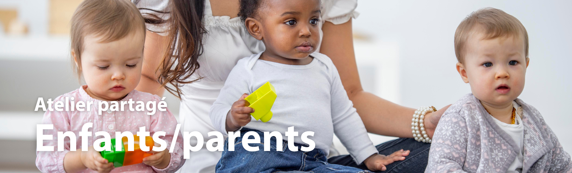 trois bébés qui jouent avec des cubes et une femme se tient assise derrière eux