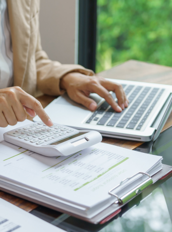 mains en train d'utiliser une calculatrice et un ordinateur portable