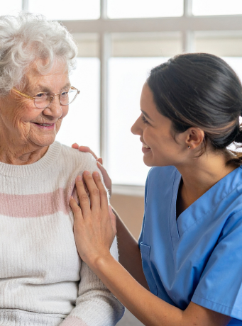 Une dame avec une blouse et une autre âgée se regardent en souriant.