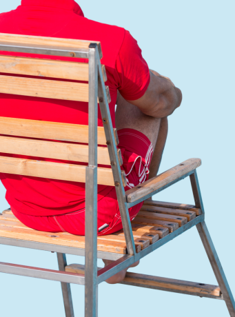 Un homme est sur une chaise de surveilllance de baignade, il s'agit d'un maitre nageur sauveteur