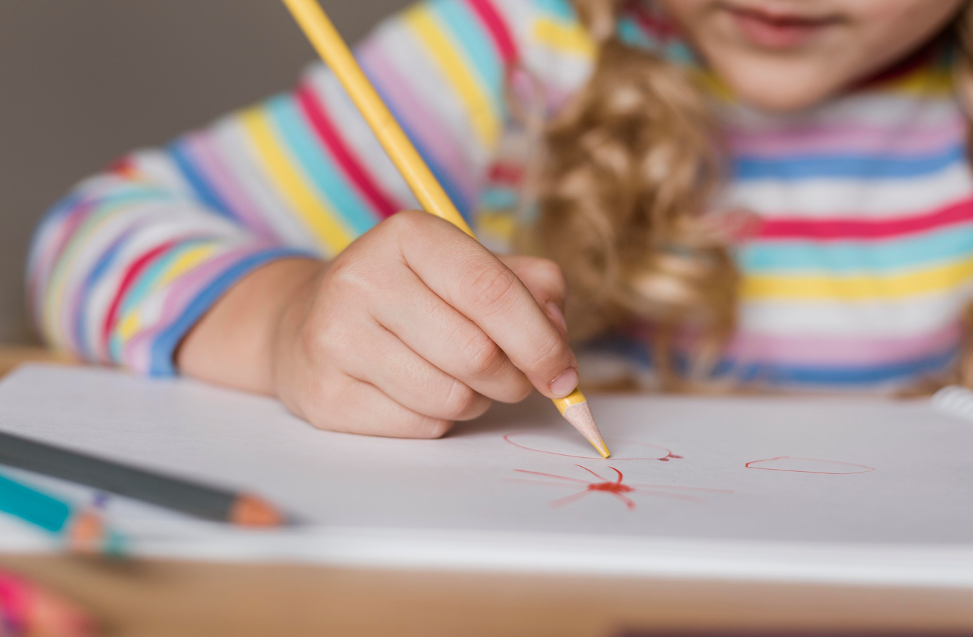 enfant qui fait un dessin avec des crayons de couleur